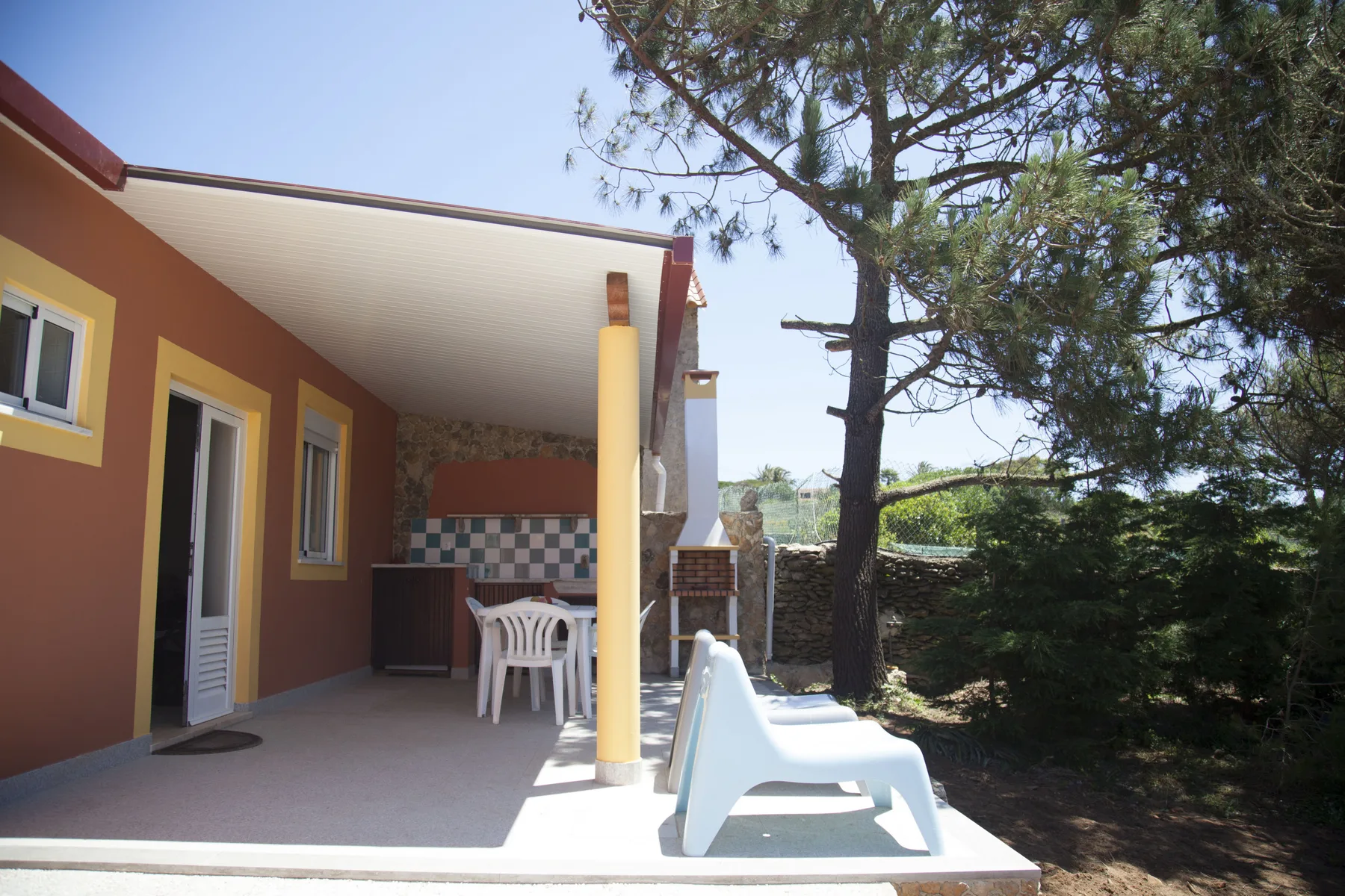 A house patio with outdoor seating beside a large tree.