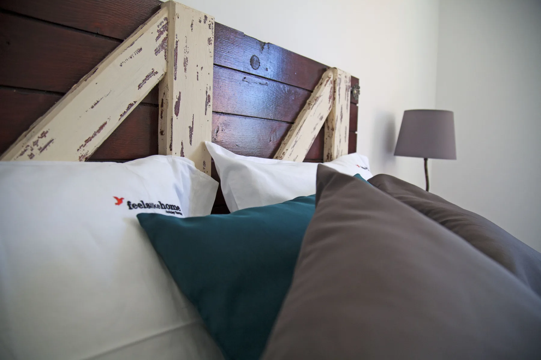 A bedroom scene with pillows arranged against a rustic wooden headboard.