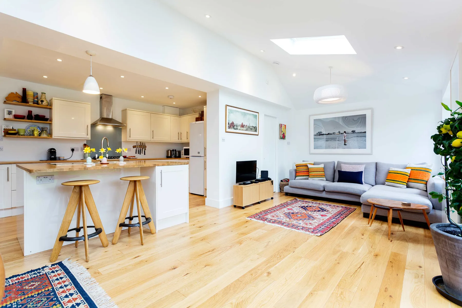 An open-plan living room and kitchen with a sofa beside a breakfast bar.