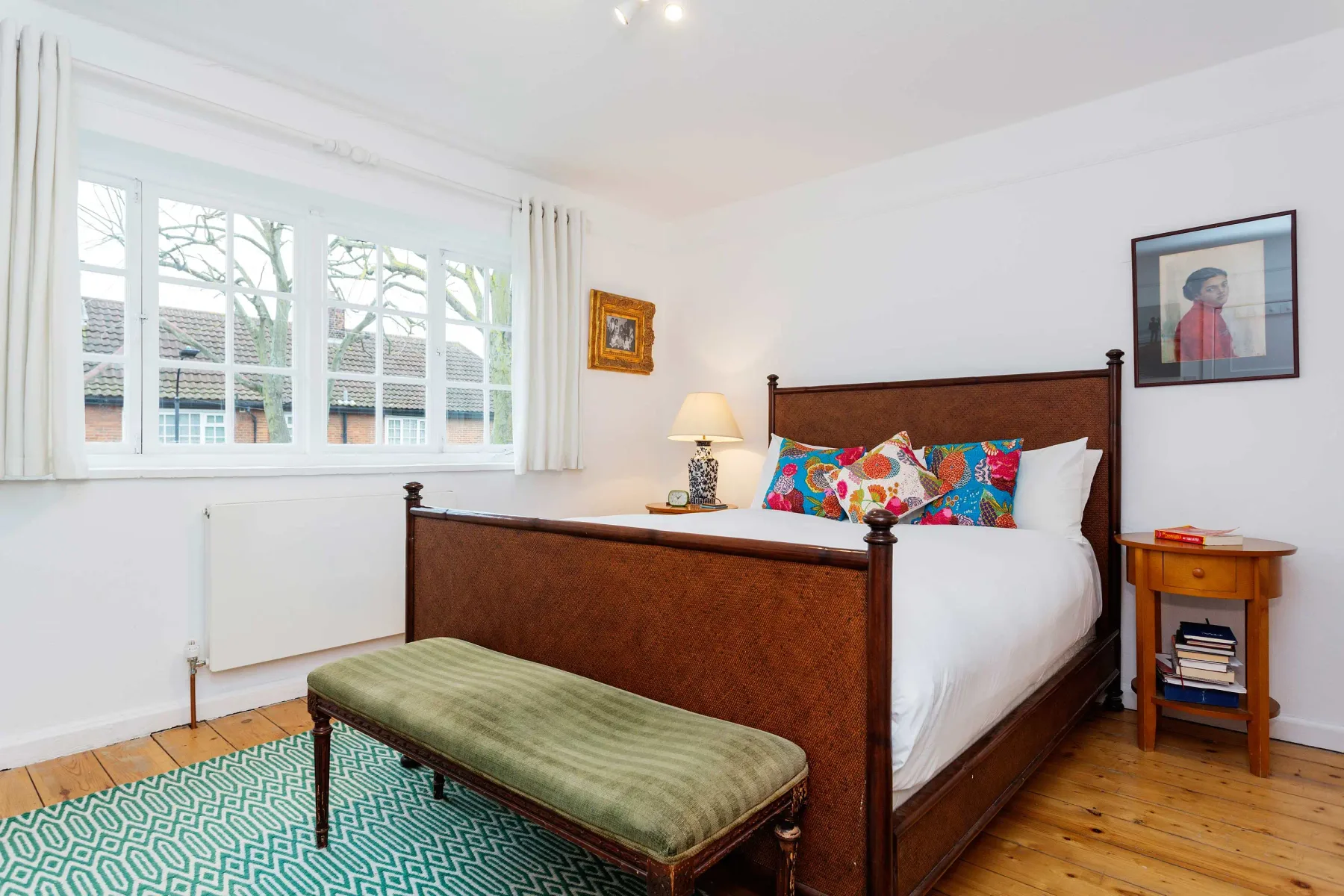 A bedroom with a wooden bed, colorful pillows, and a large window.