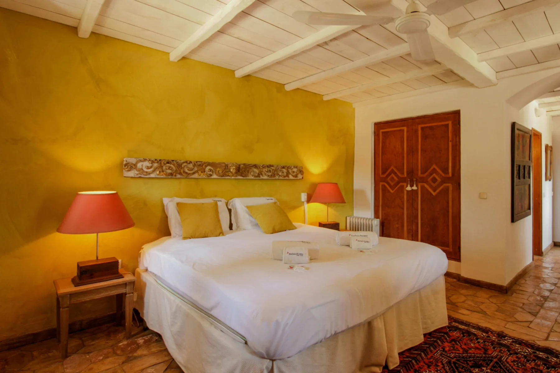 Un dormitorio con una cama grande bajo vigas blancas expuestas.