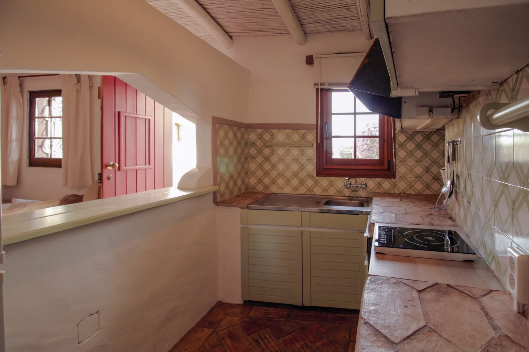 Una cocina compacta con encimeras de azulejos, una placa de cocción y una ventana.