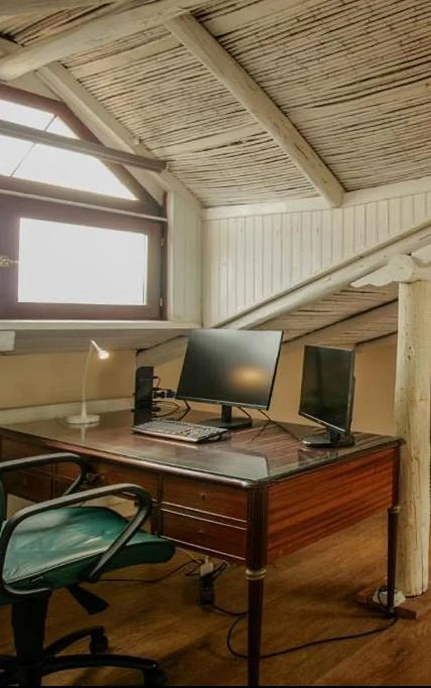 Un espacio de trabajo compacto con escritorio de madera, monitores y una silla de oficina.