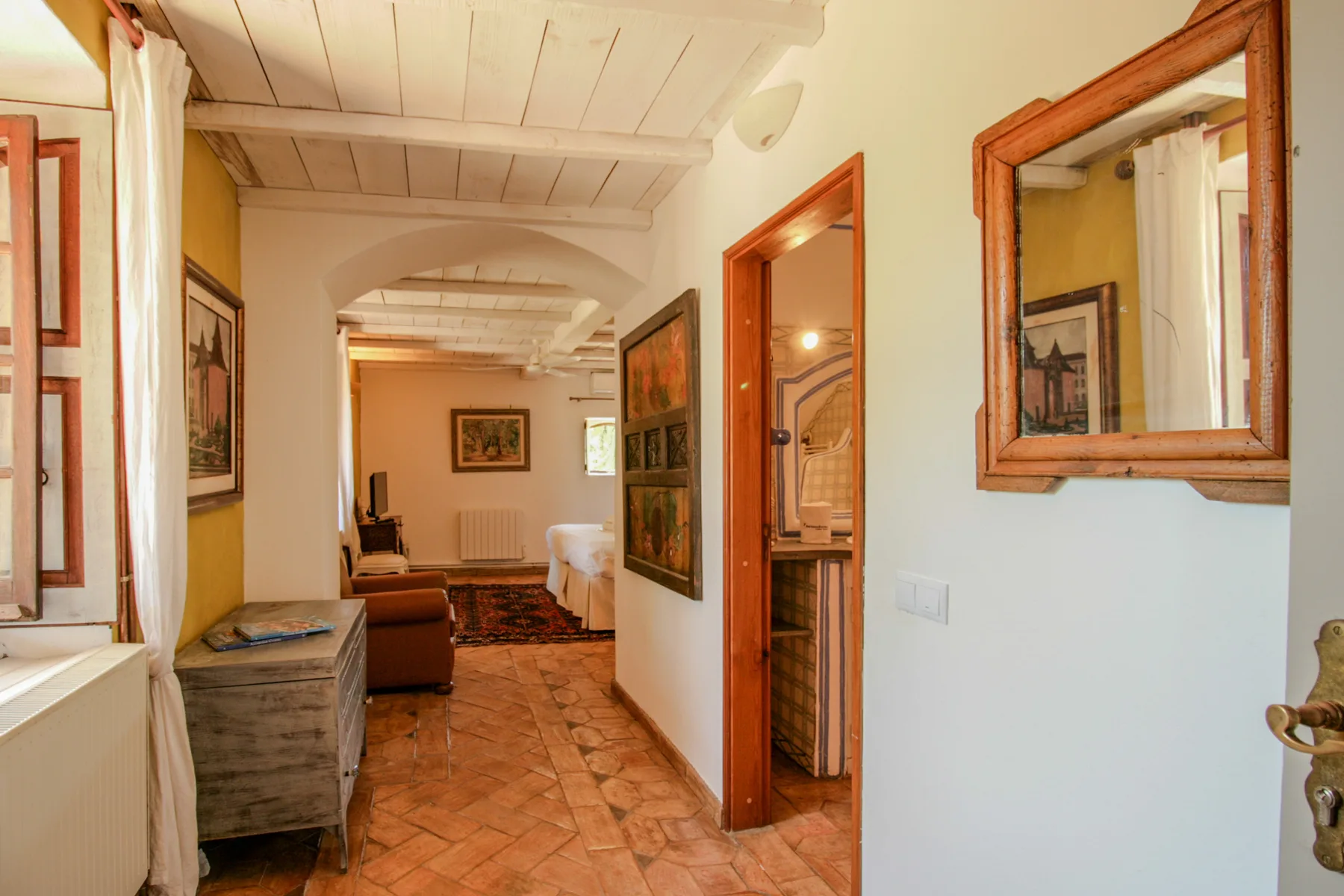 Un pasillo con suelo de baldosas, puertas de madera y cuadros enmarcados.