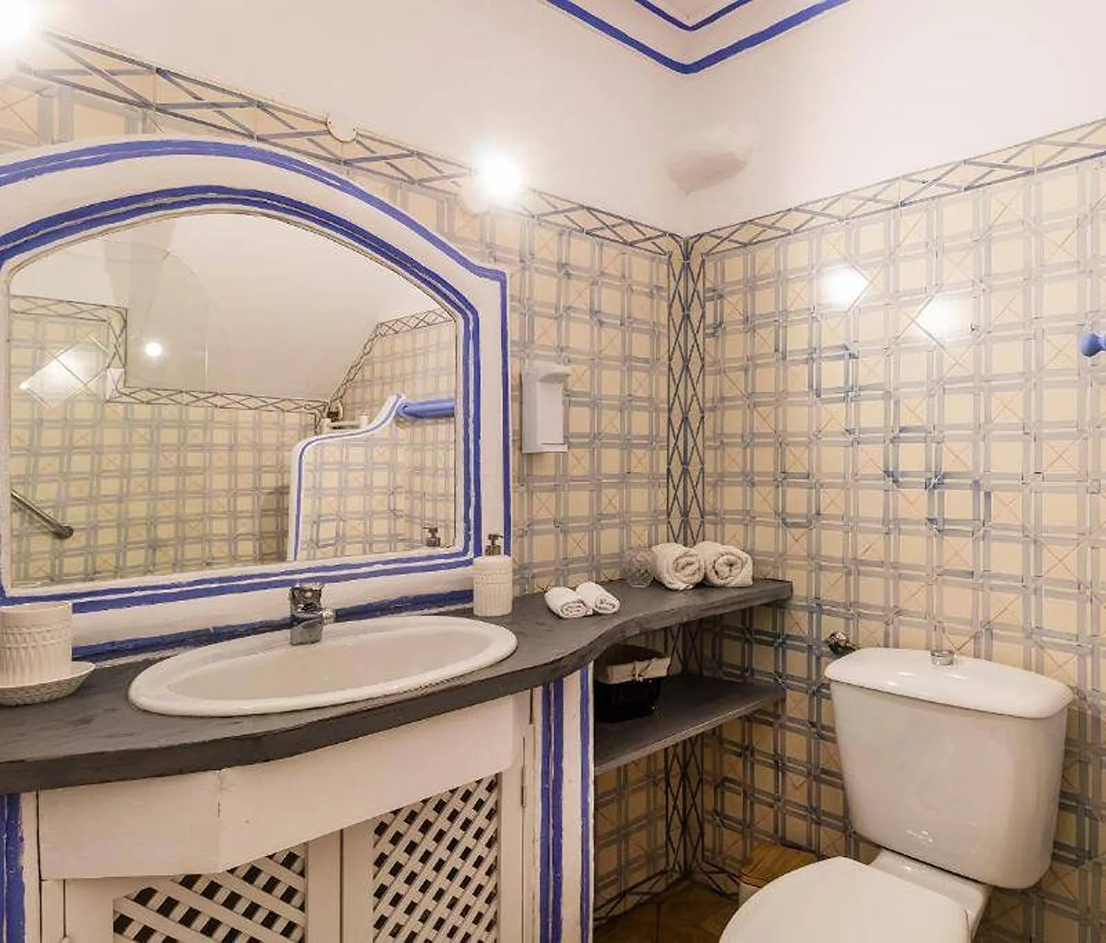 Un baño alicatado con lavabo, espejo e inodoro.