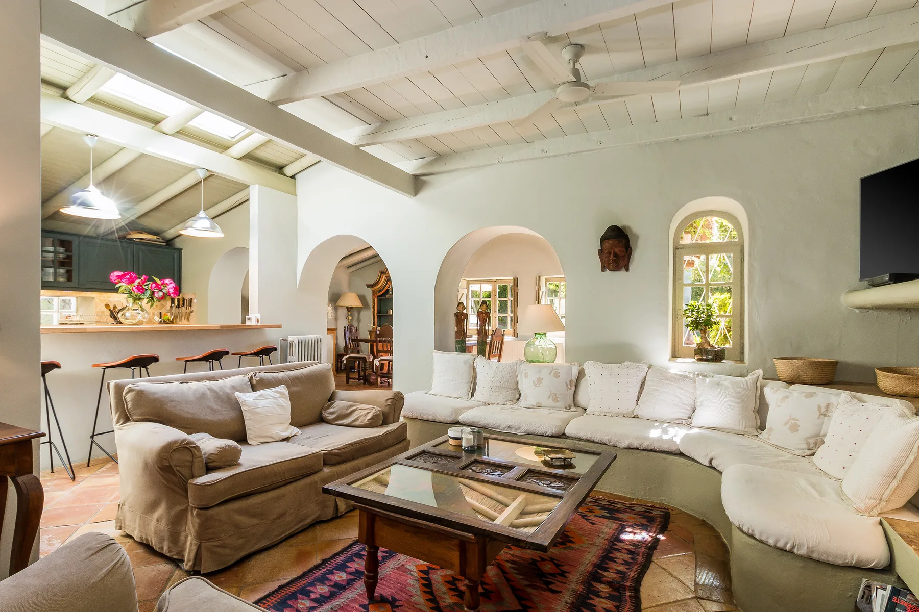 A living room with pale seating, a coffee table, and arched openings.