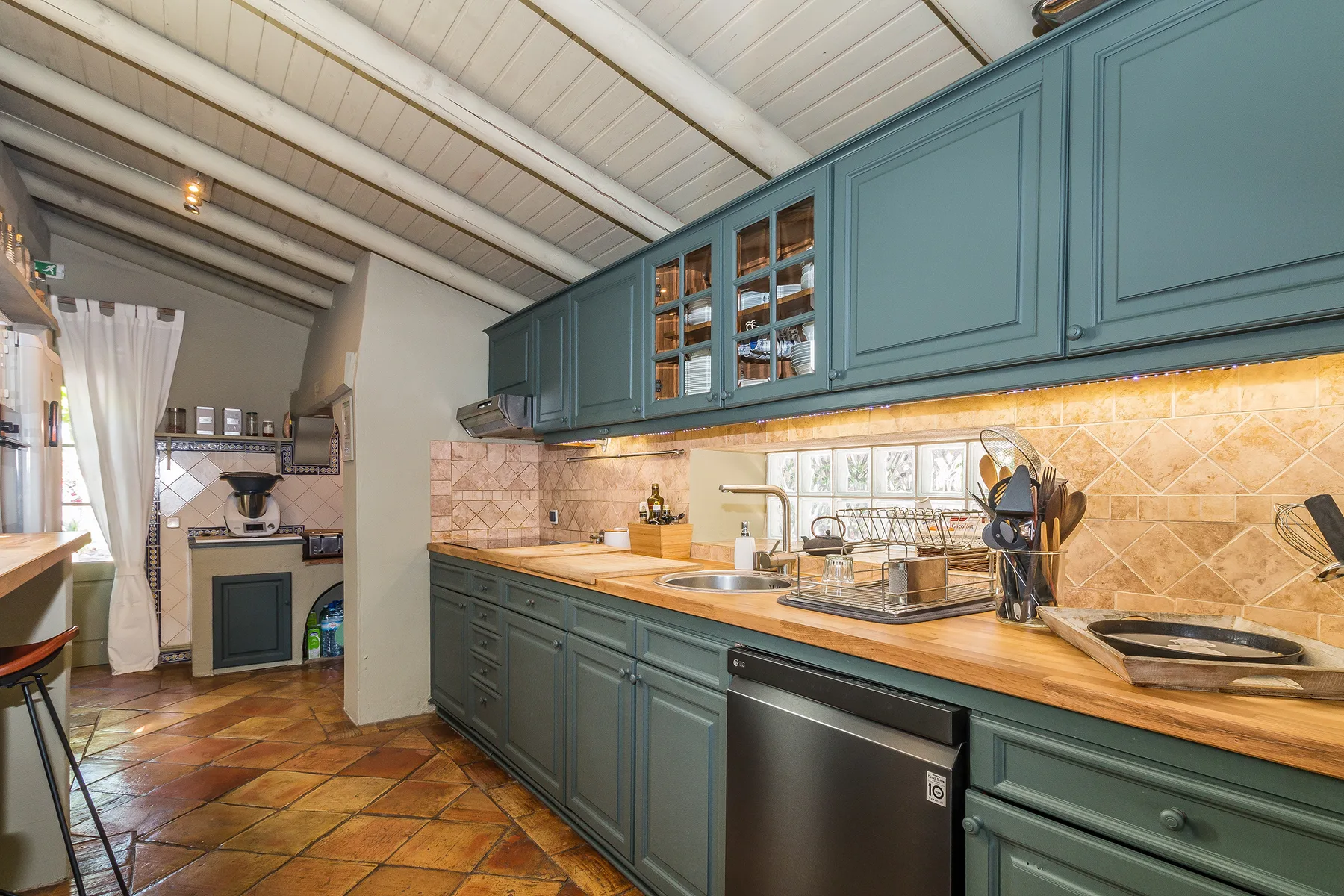 Una cocina con armarios azules, un salpicadero de azulejos y una encimera larga.