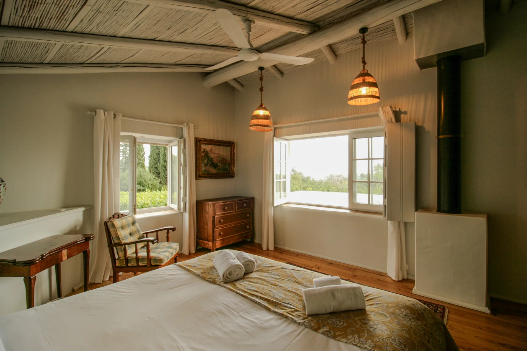 Un dormitorio con una cama, ventanas y un techo de madera.