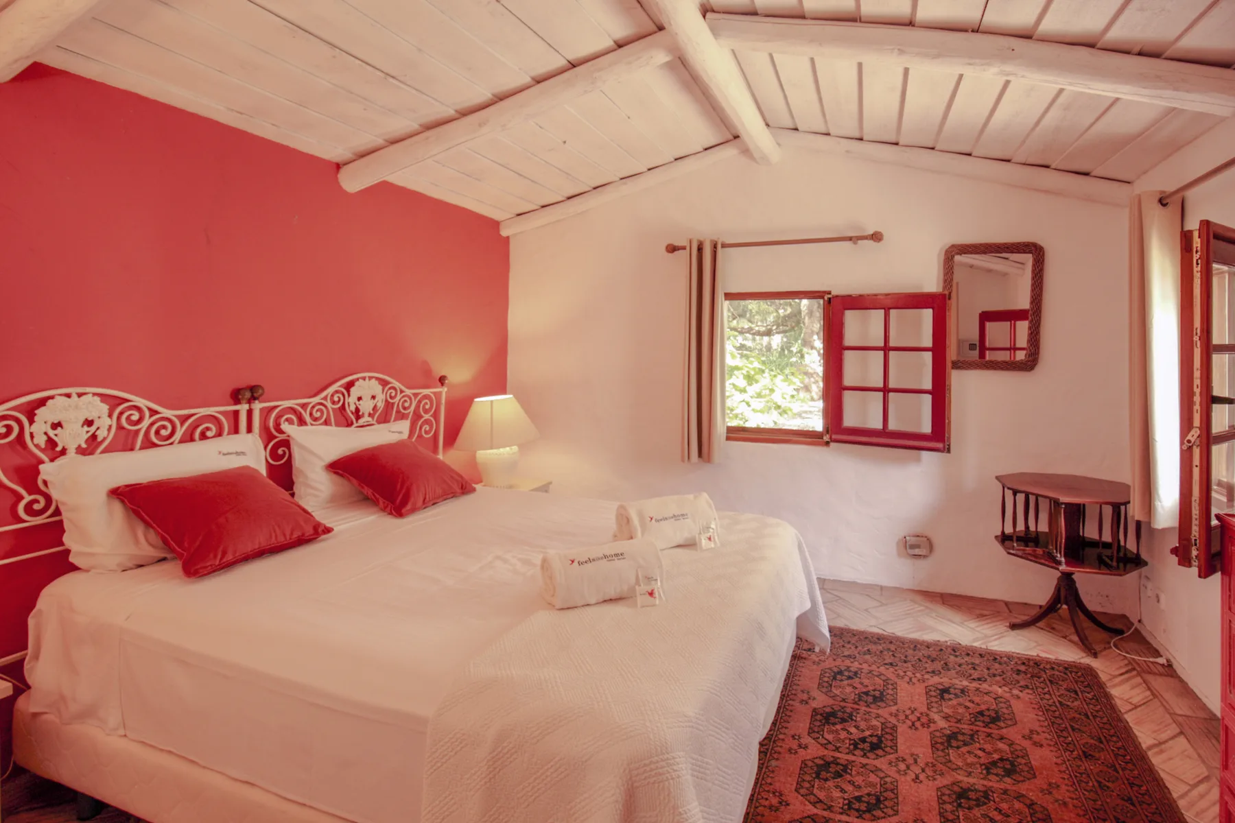 Un dormitorio con una cama, una pared roja y una ventana.