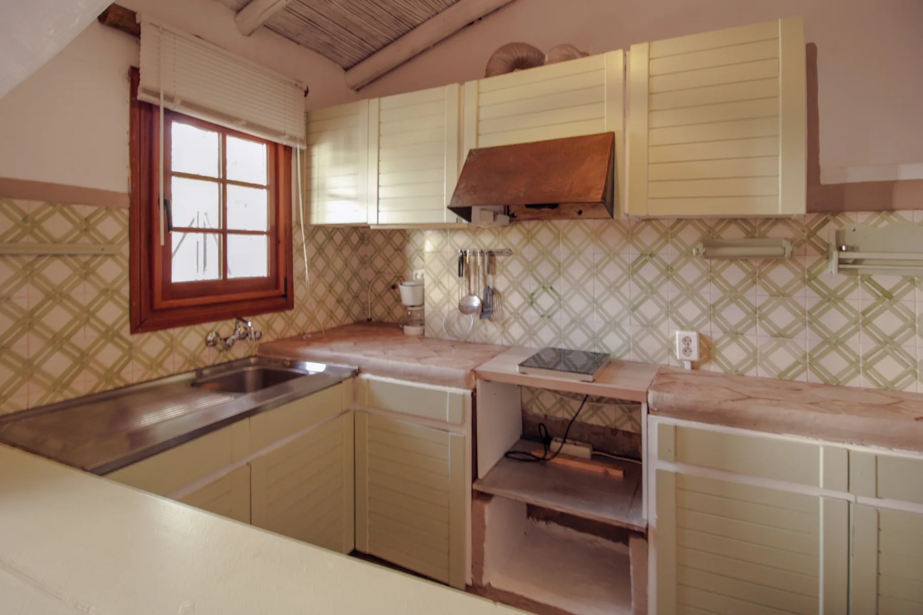 Una cocina con armarios claros, un salpicadero de azulejos y una ventana.