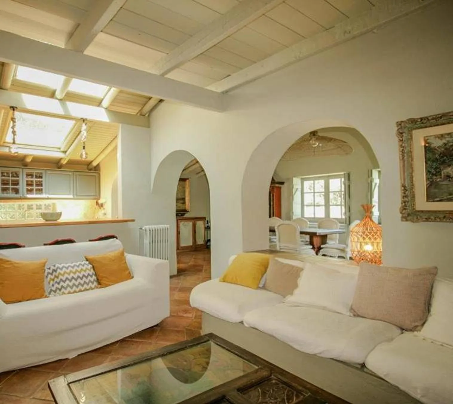 Una sala luminosa con asientos y arcos que dan al comedor.
