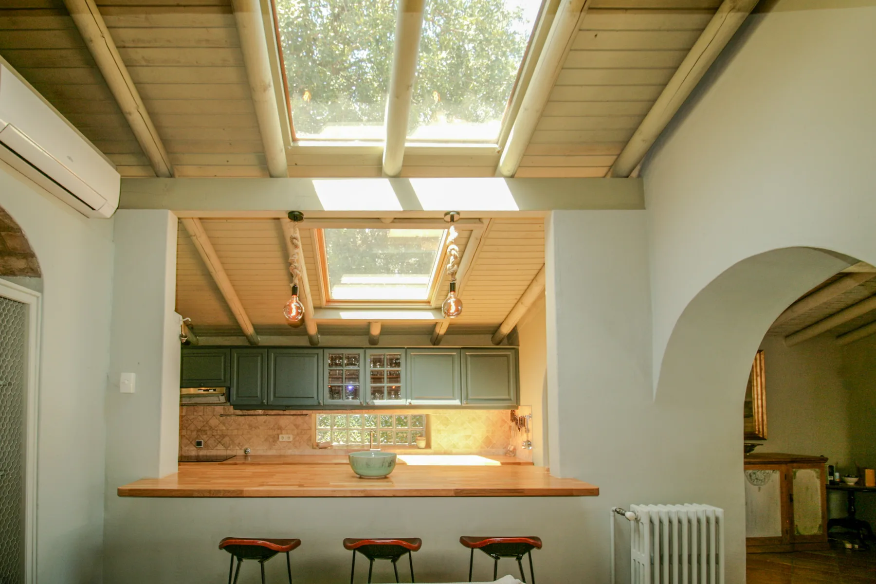 Una cocina luminosa con una barra de madera bajo un tragaluz grande.