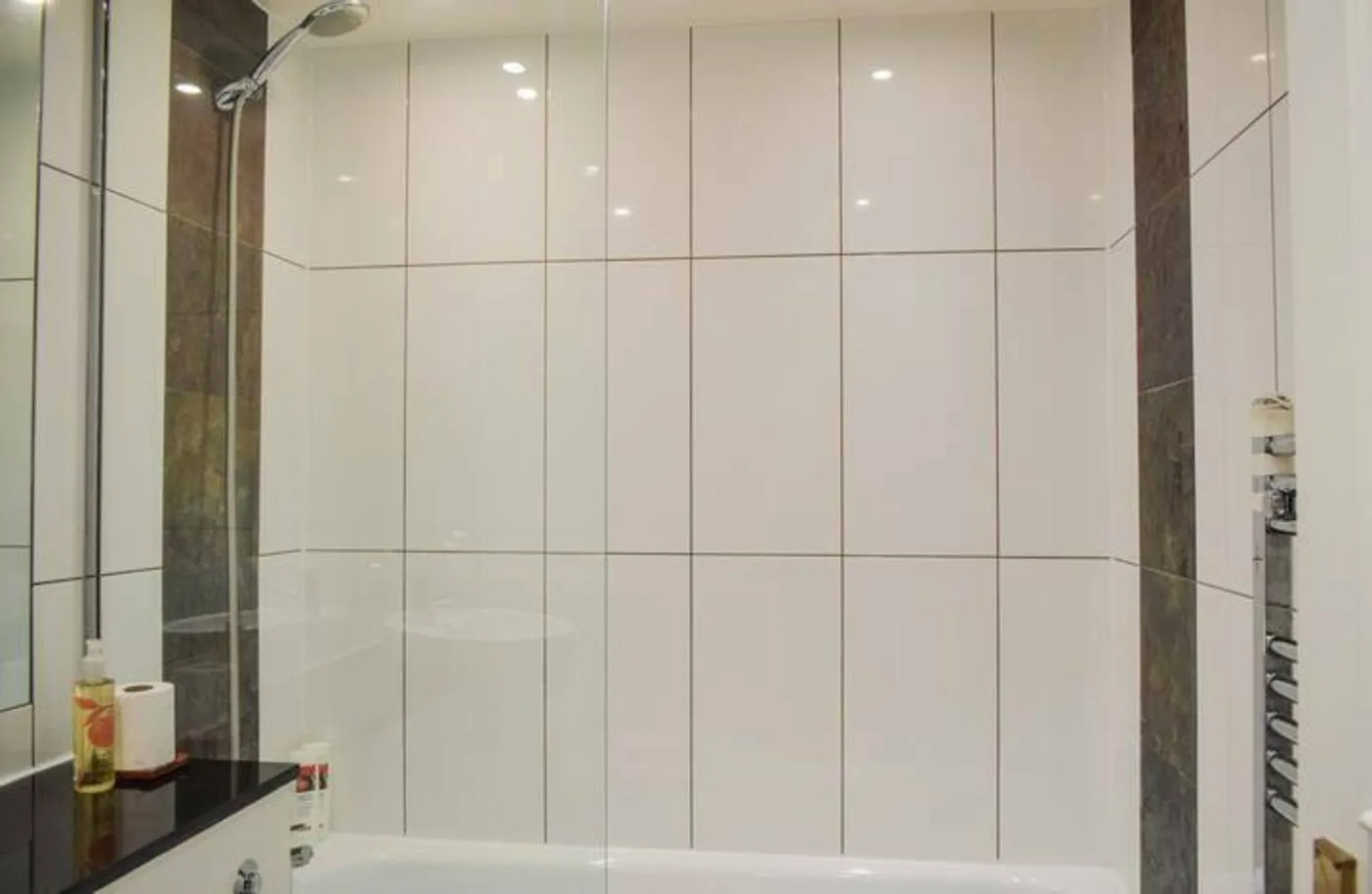 A tiled bathroom shower area with a wall-mounted showerhead.