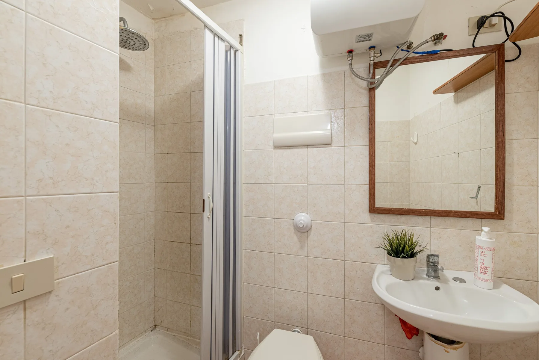 A tiled bathroom with a shower, sink, and wall mirror.