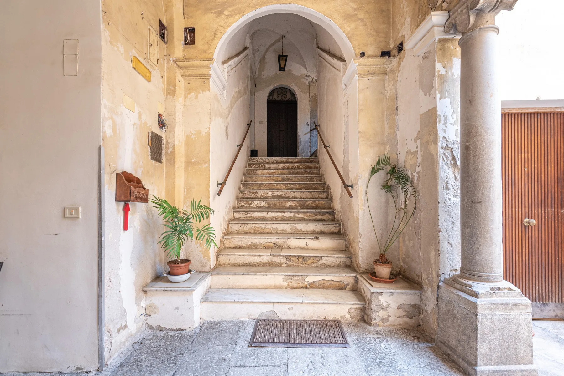 An old stone entry hall with a central staircase leading to an arched doorway.