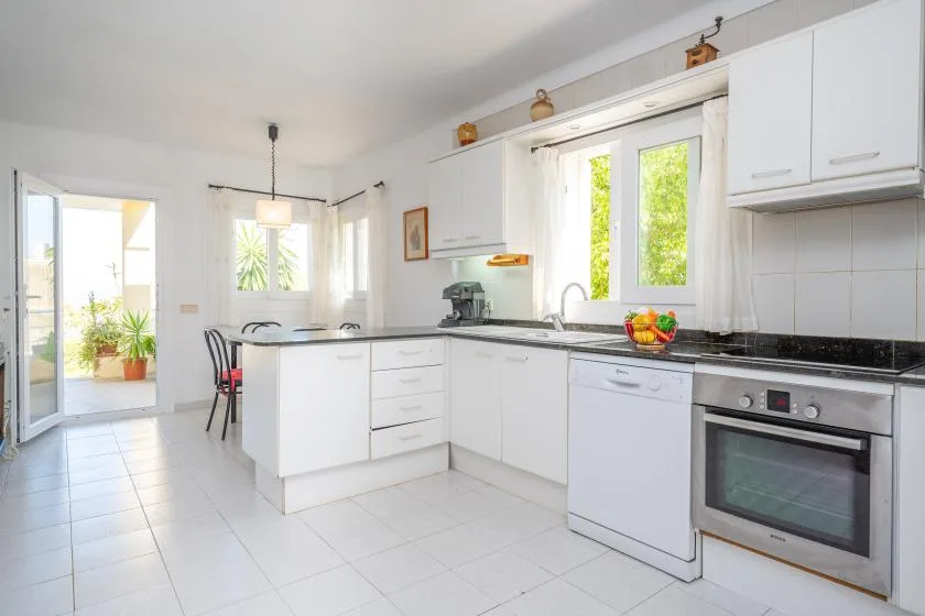 A bright kitchen with white cabinets, a central island, and large windows.