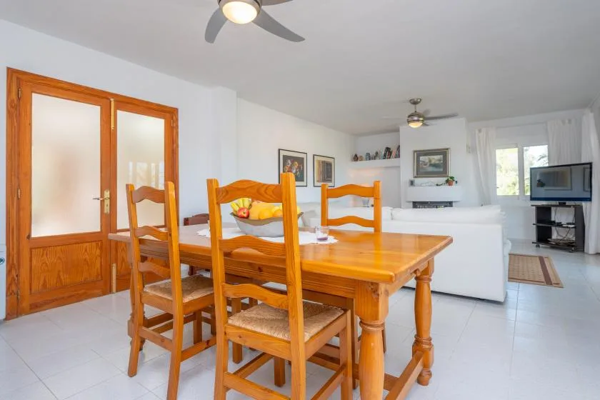A dining area with a wooden table and chairs opens into a living room.