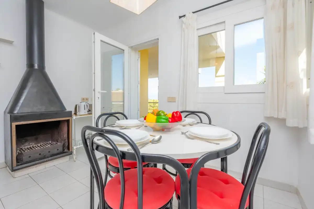 A dining area with a table, red-seated chairs, and a fireplace.