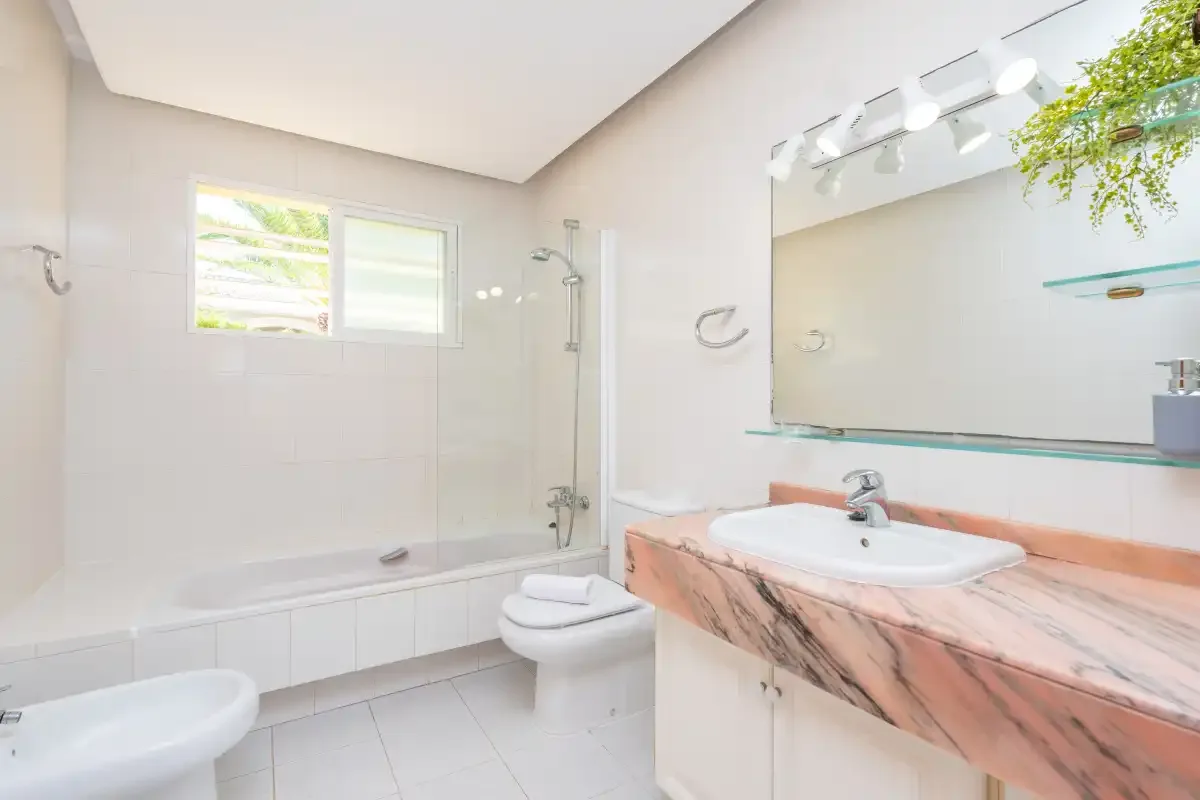 A bright bathroom with a bathtub, toilet, and wide vanity.