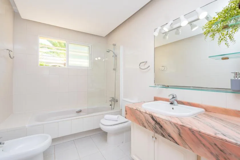 A bright bathroom with a bathtub, toilet, and vanity.
