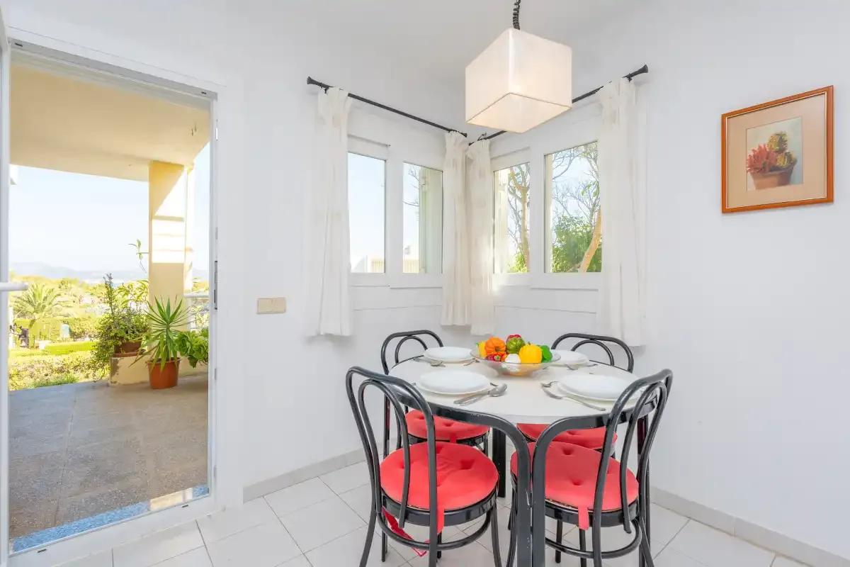 A bright dining area with a round table and red-cushioned seating.