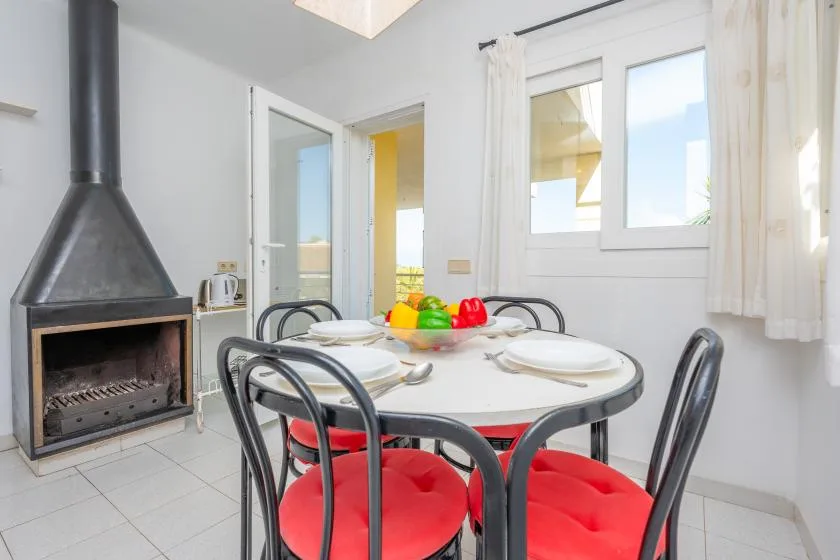 A dining area with a round table and red-cushioned seating beside a fireplace.