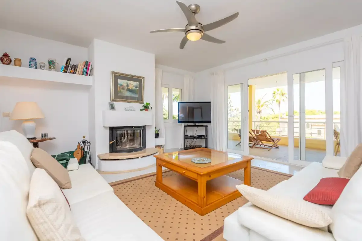 A bright living room with seating, a coffee table, and glass doors opening onto a terrace.