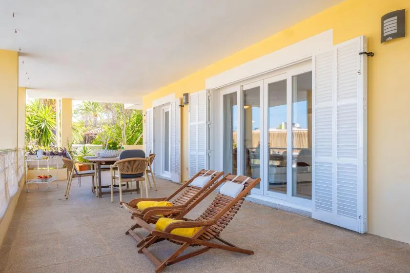 A covered patio with lounge seating and doors opening onto a garden.