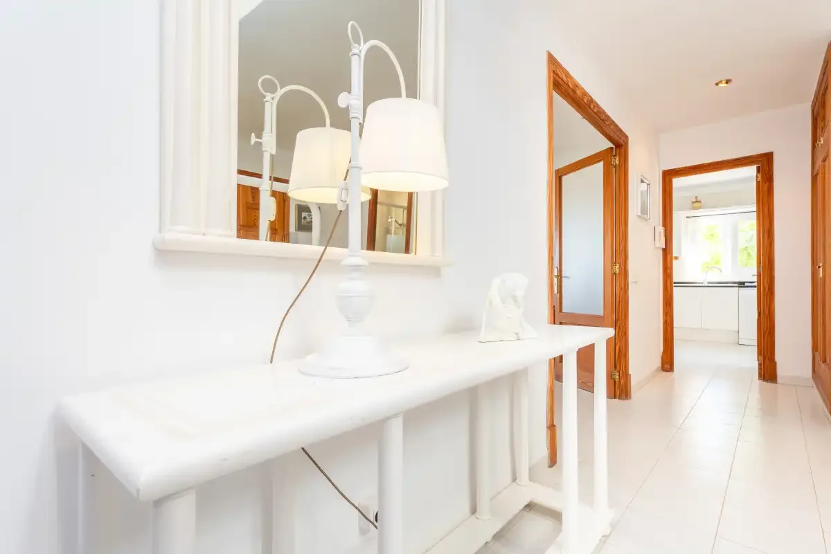 A bright hallway with a white console table and a view into the kitchen.