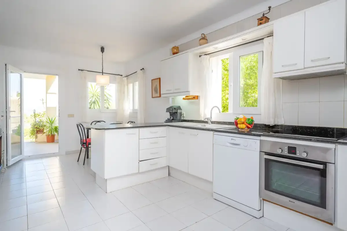 A bright kitchen with white cabinets, a central island, and large windows.