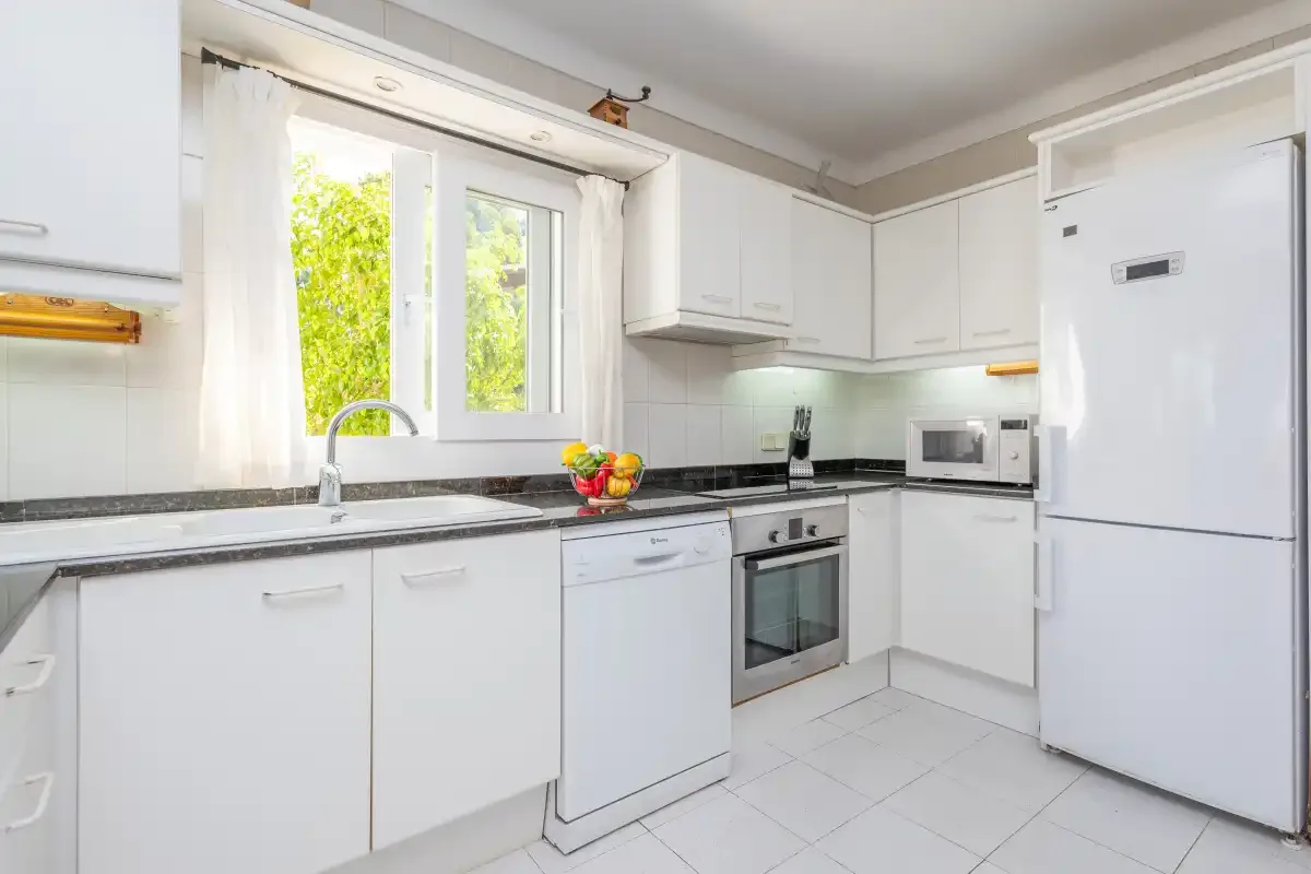 A bright kitchen with white cabinets and a window above the counter.