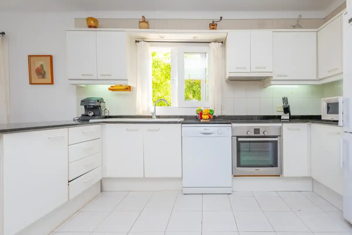 A bright kitchen with white cabinets, a countertop, and a window.