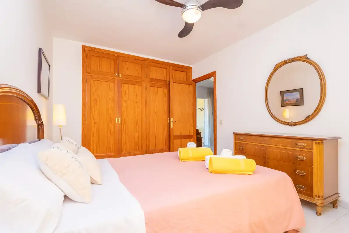 A bedroom with a bed, wooden wardrobes, and a dresser.