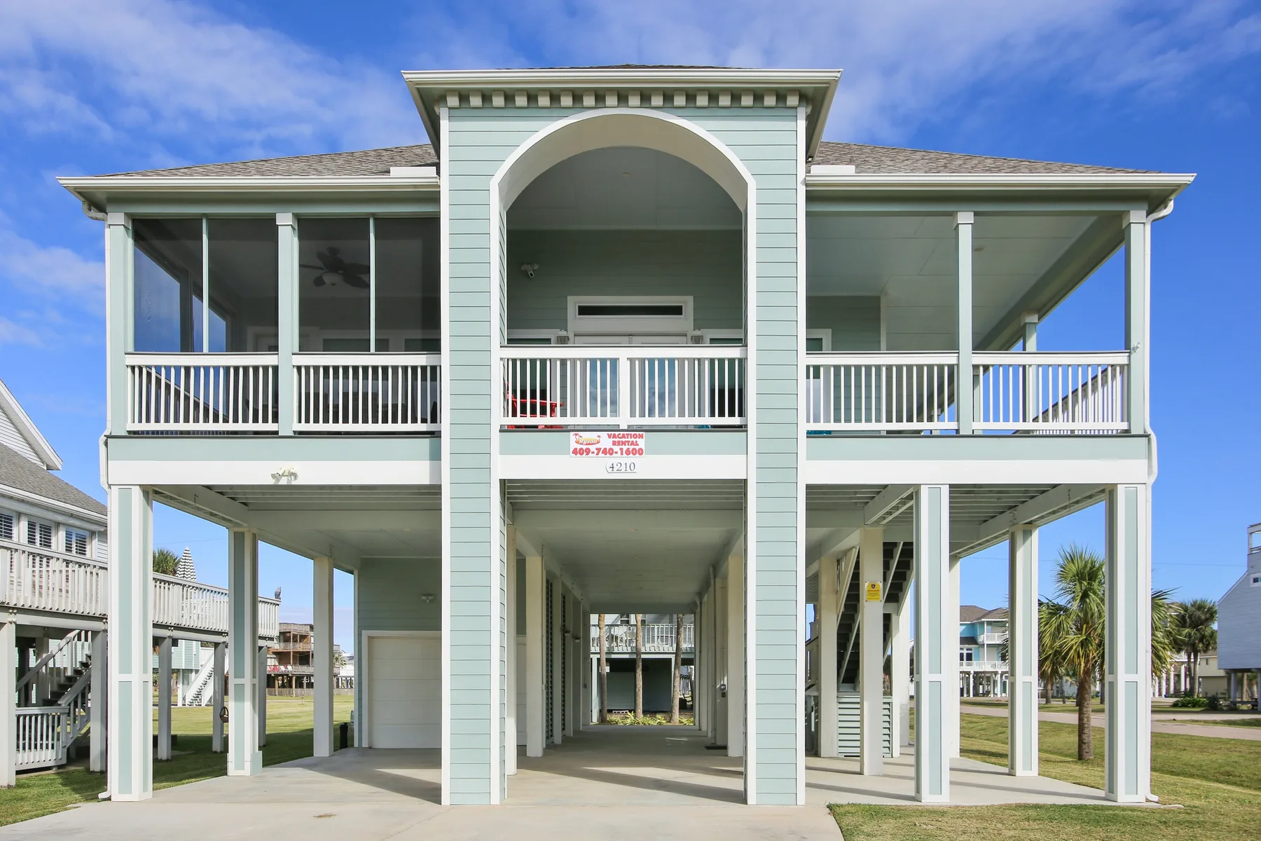 A raised coastal-style house with screened upper porches and an open ground level.