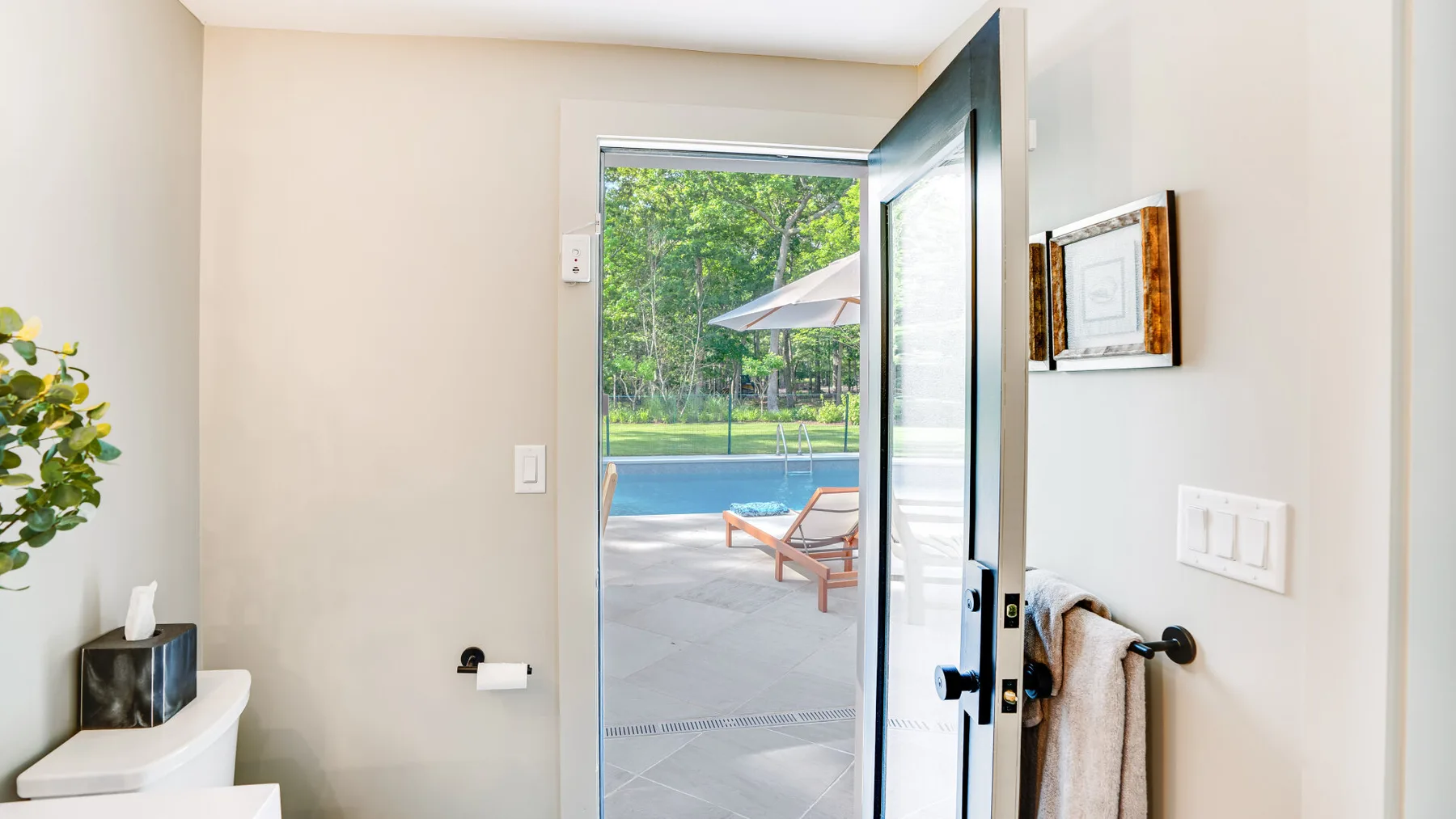An open doorway leads to a patio beside a swimming pool.