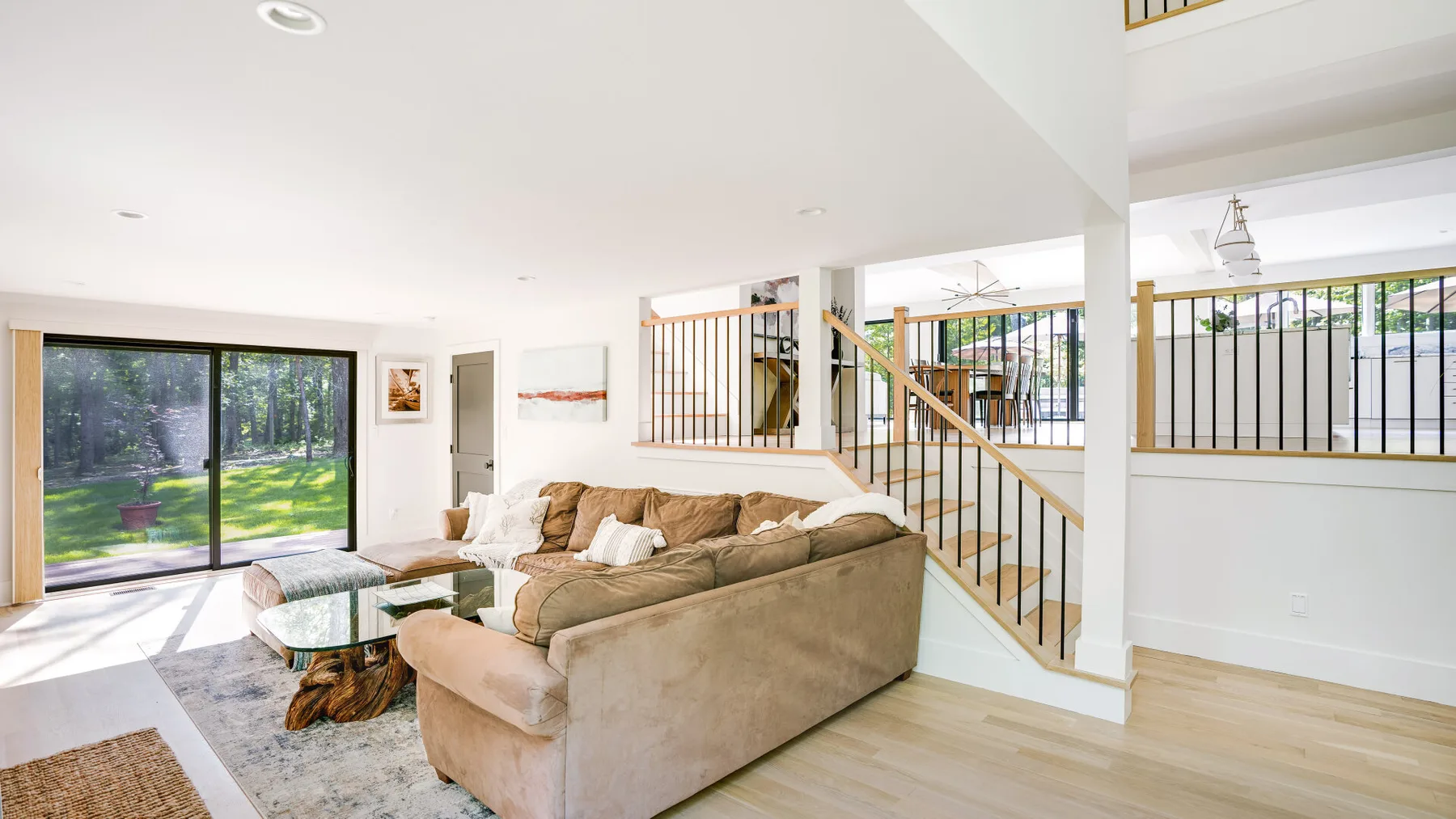 A bright living room with a sectional seating area beside large sliding glass doors.