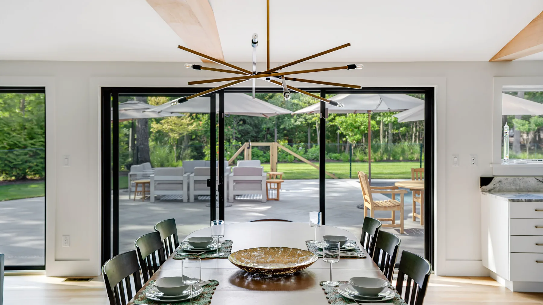 A dining area with a table and chairs faces large glass doors opening onto a patio.