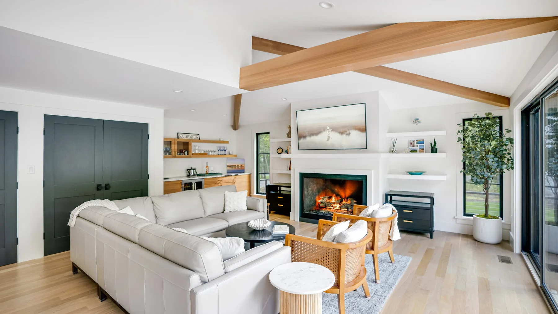 A bright living room with white seating around a fireplace.