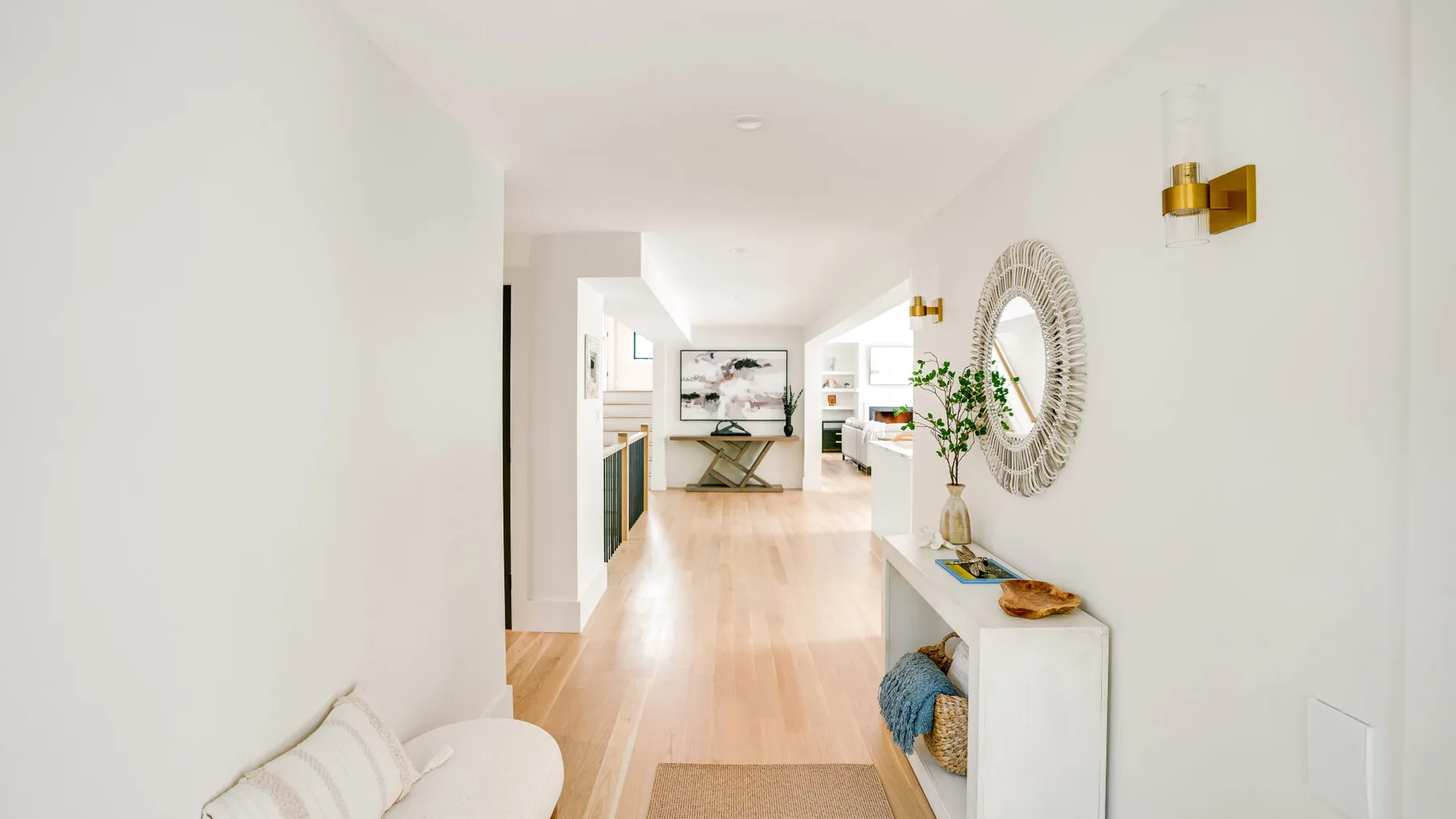 A bright hallway opens toward a living area, with a console and wall mirror.