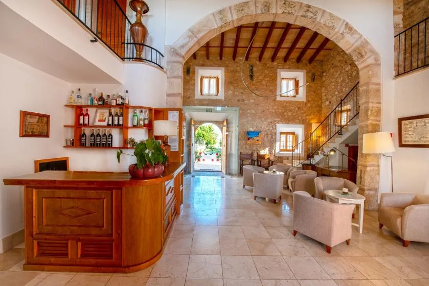 Un amplio interior con mostrador de madera, zona de asientos y arco de piedra.