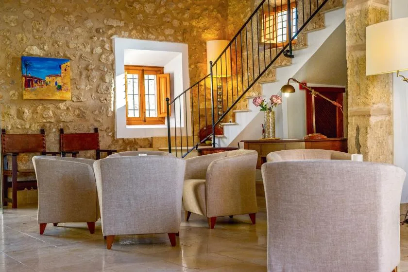 Comedor con paredes de piedra, asientos tapizados y una escalera.