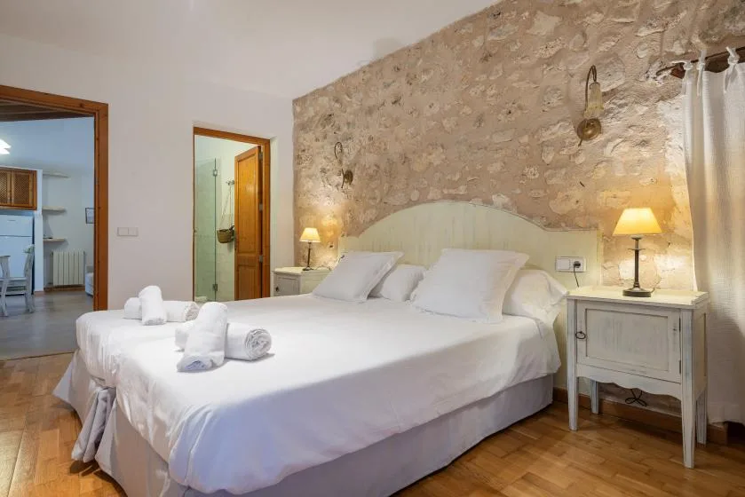 Un dormitorio con una cama grande, mesitas de noche y una pared de piedra vista.
