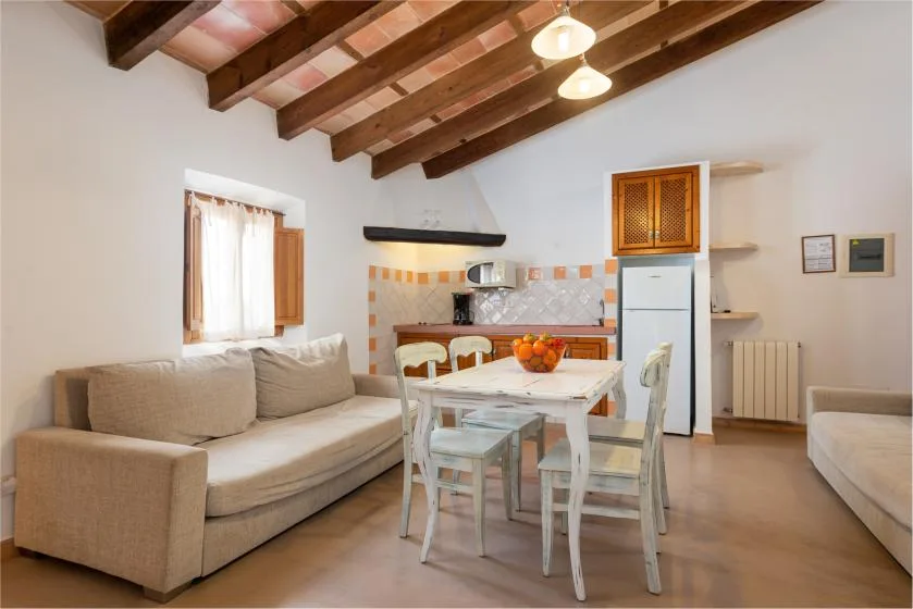 Una sala de estar y comedor con sofá, mesa y cocina compacta.