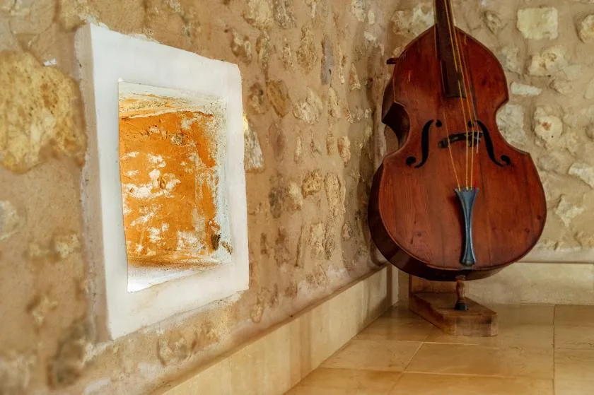 Un contrabajo y una obra enmarcada están junto a una pared de piedra texturizada.