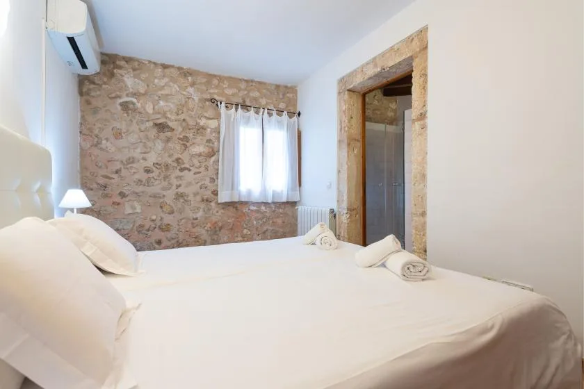 Un dormitorio con una cama grande, una pared de piedra y una ventana con cortinas.
