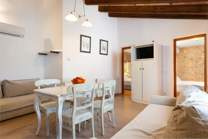 Una sala y comedor con mesa, asientos y un mueble para televisión.