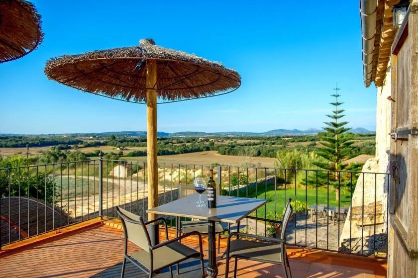 Una terraza con mesa y asientos da a un paisaje verde de campo.
