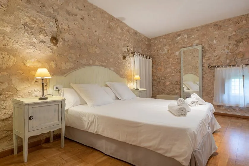 Un dormitorio con una cama grande, una mesita de noche y paredes de piedra vista.