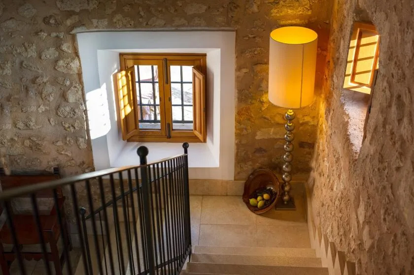Una escalera de piedra con una ventana de madera y una lámpara de pie.