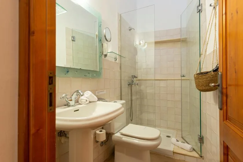 Un baño con lavabo, inodoro y mampara de ducha de vidrio.
